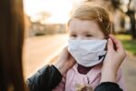 Parent helping child put on face mask